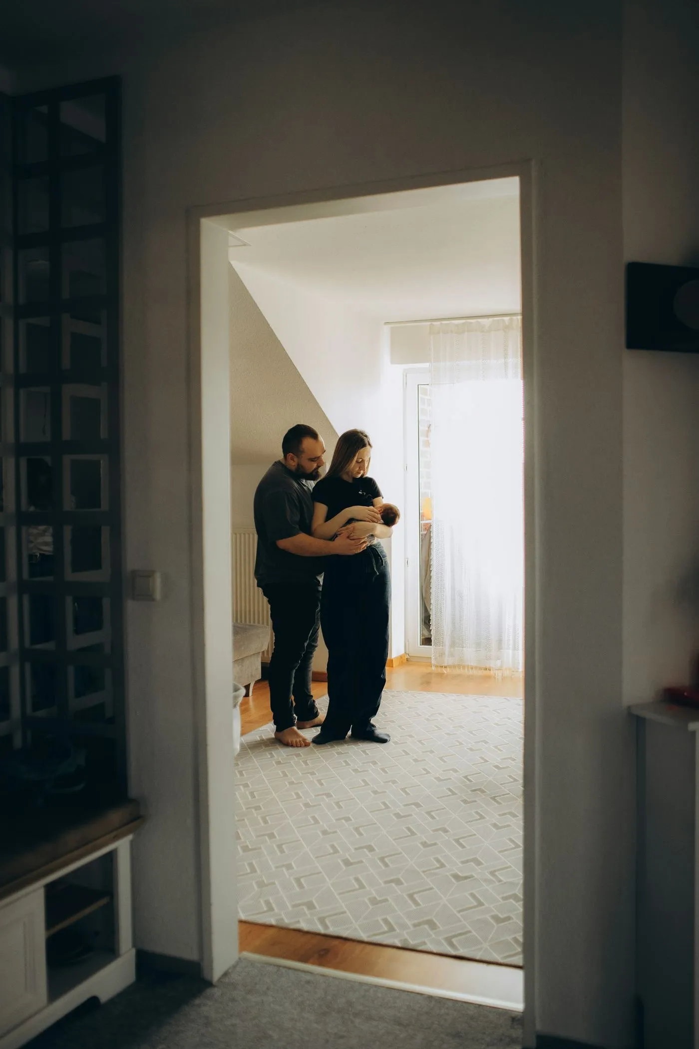 Rodzice z noworodkiem na rękach przy jasnym oknie