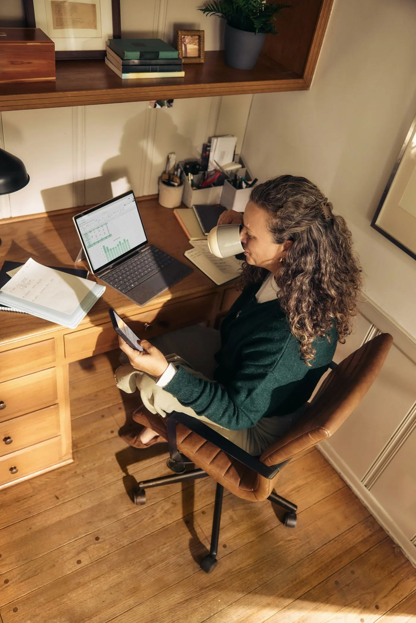 A woman working at a wooden desk with a laptop